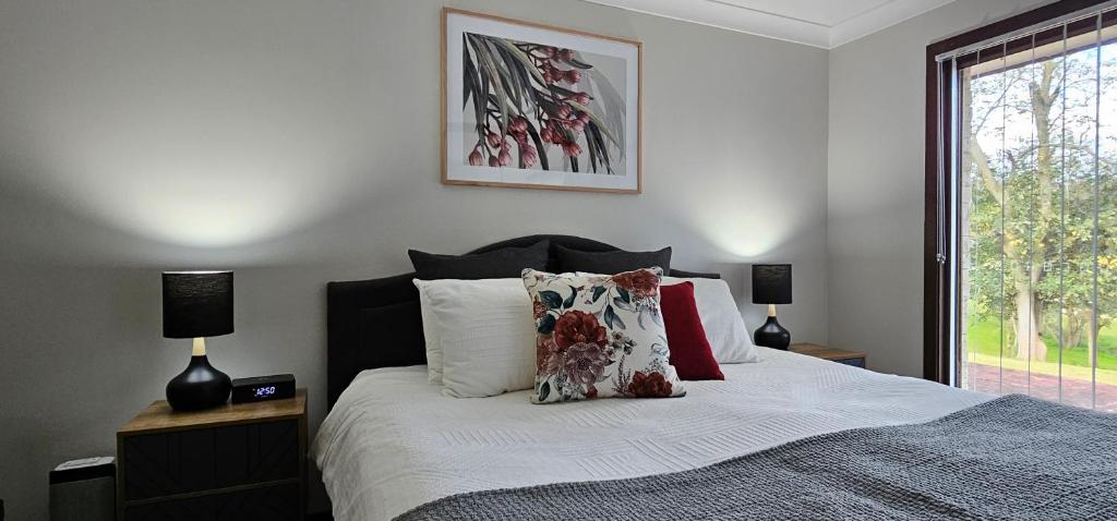 a bedroom with a bed with two lamps and a window at Serendipity On Barrington in Barrington