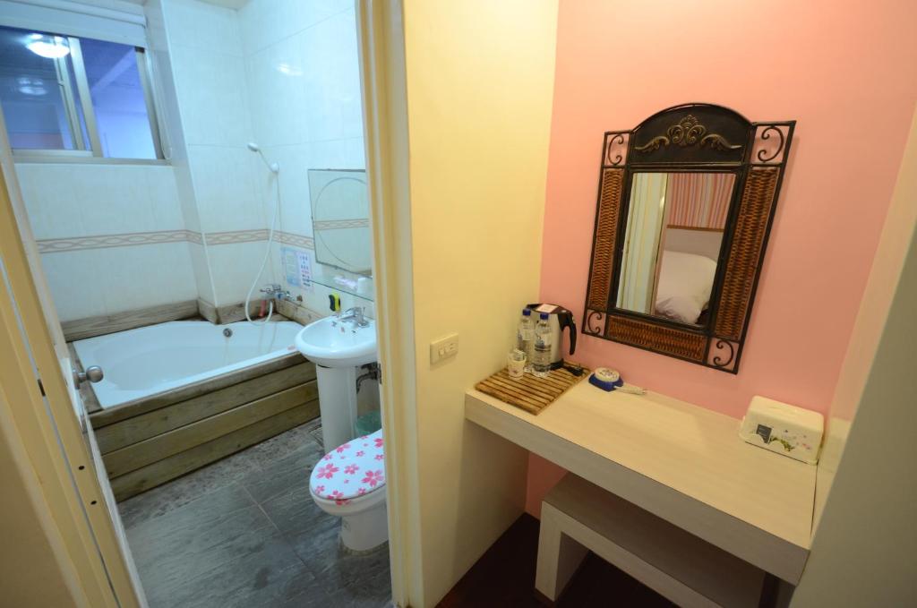 a bathroom with a sink and a toilet and a mirror at Cocos Hot Spring Hotel in Ruisui