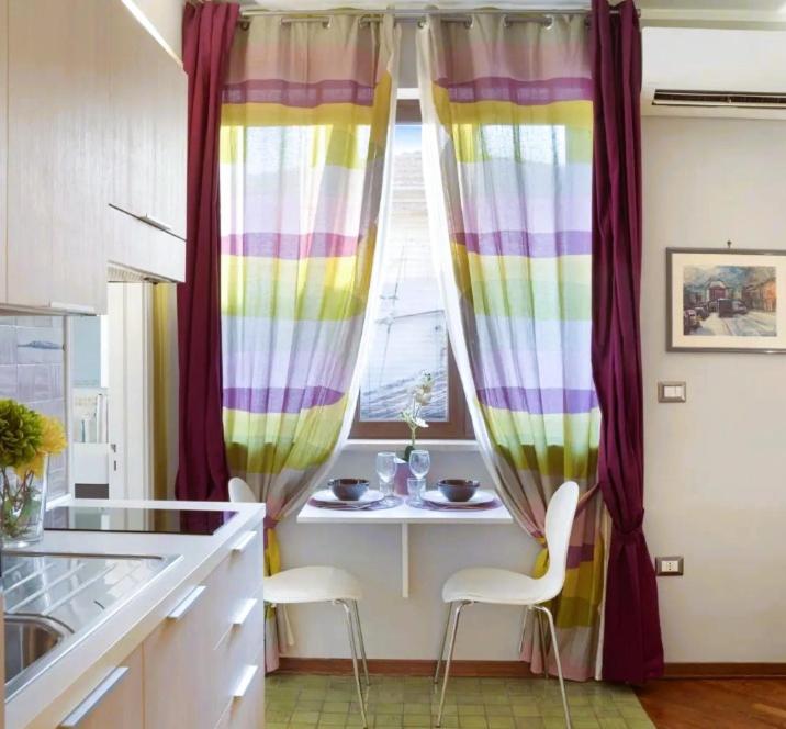 een keuken met kleurrijke gordijnen en een tafel en stoelen bij Central Apartment in Salerno