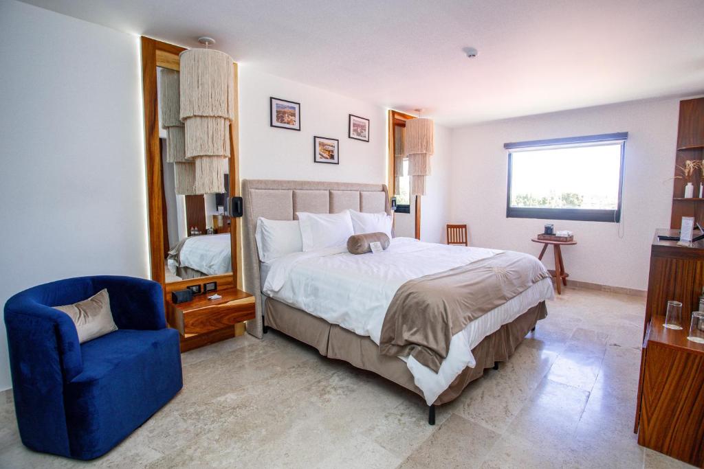 a bedroom with a bed and a blue chair at Hotel Guiant in Santa María del Río