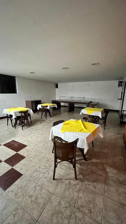 a room with tables and chairs with yellow tables at Hotel Monick in Teixeira de Freitas