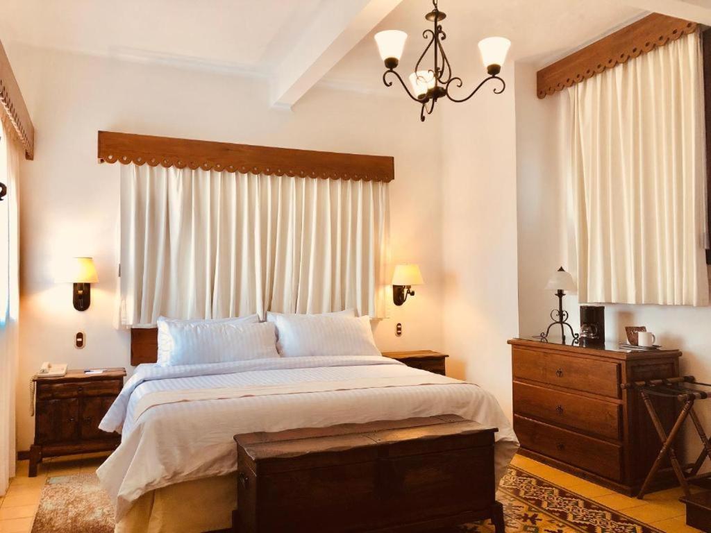 a bedroom with a large bed and a chandelier at HOTEL MI SOLAR EJECUTIVO in Uruapan del Progreso