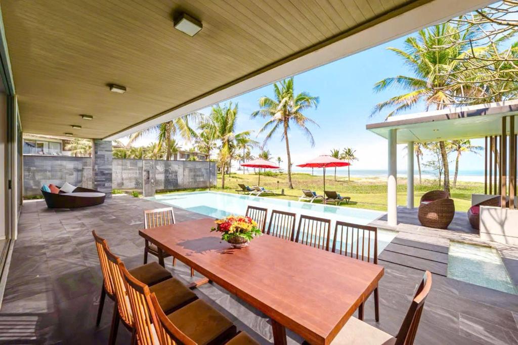 a dining room with a table and a swimming pool at Danang Villas Complex in Da Nang