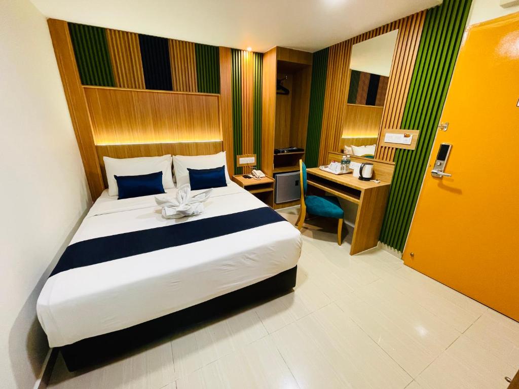 A compact double room with a large bed, built-in desk, mirror, and bold green-and-wood decor.