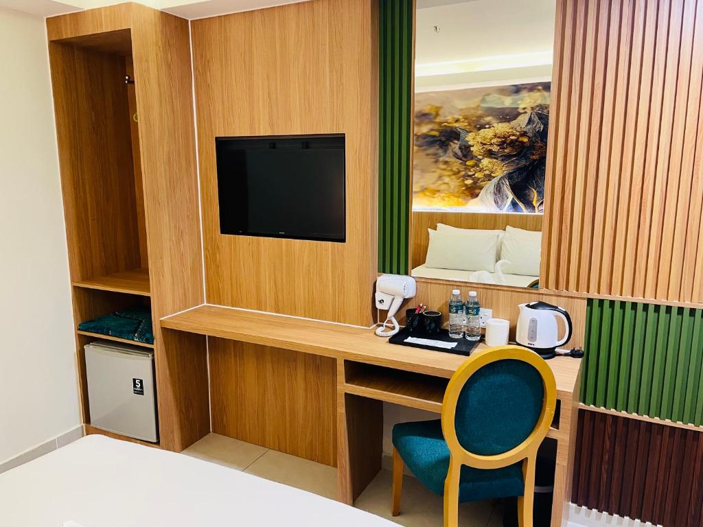 An in-room desk with television, chair, minibar, kettle, and refreshment supplies.