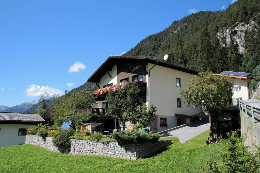 une maison avec des fleurs sur le côté d'une montagne dans l'établissement Gästehaus Scherl, à Pettneu am Arlberg