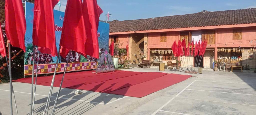 a red rug in front of a building with red flags at Mùa Pửi Lô lô homestay in Mèo Vạc