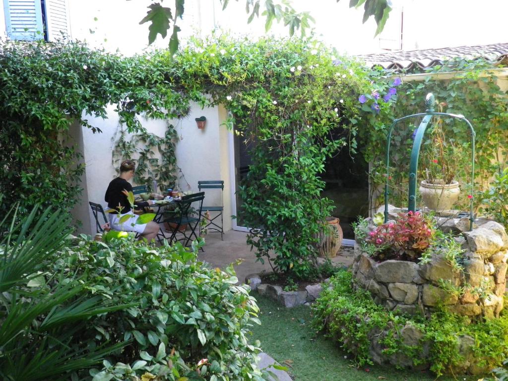 um homem sentado à mesa num jardim em Chez Catherine em Roquebrune-sur-Argens