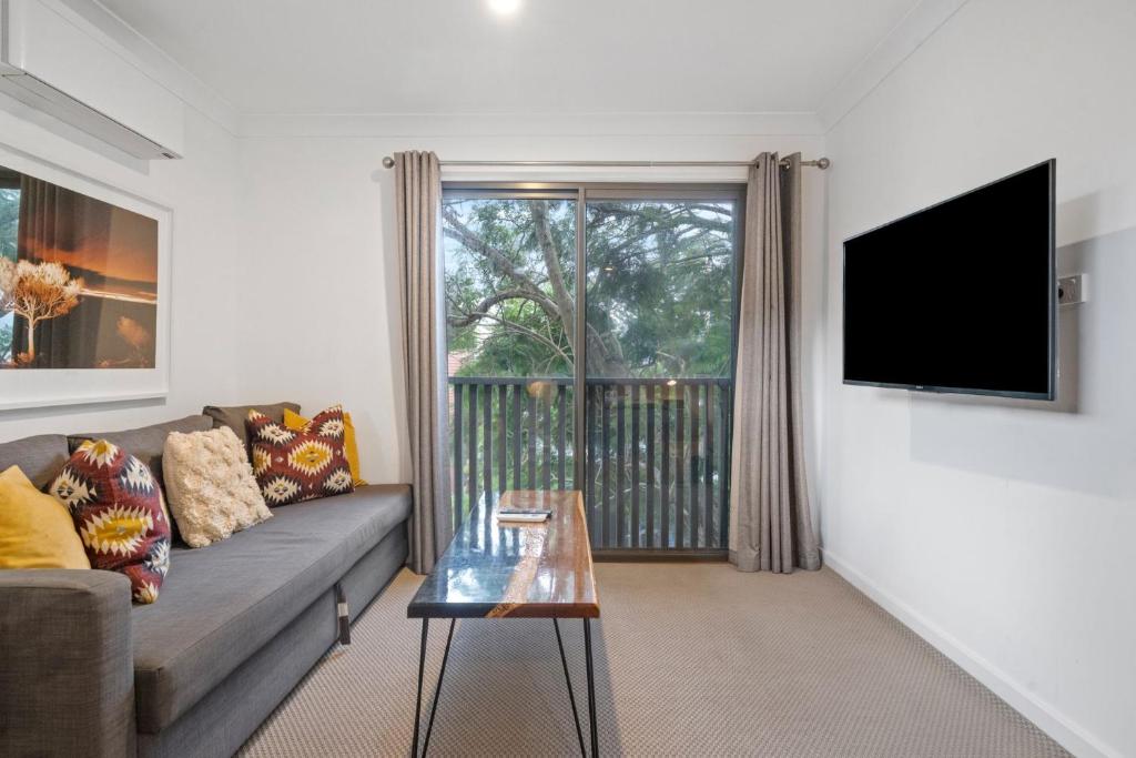 Una sala de estar con un sofá y un televisor de pantalla plana. en Gorgeous Self Contained Home, en Sídney