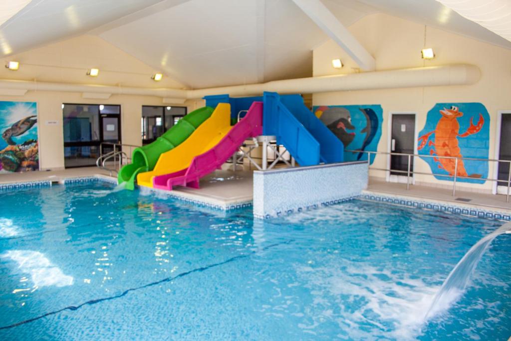 a swimming pool with a water slide in a building at Crows Nest Caravan Park in Filey