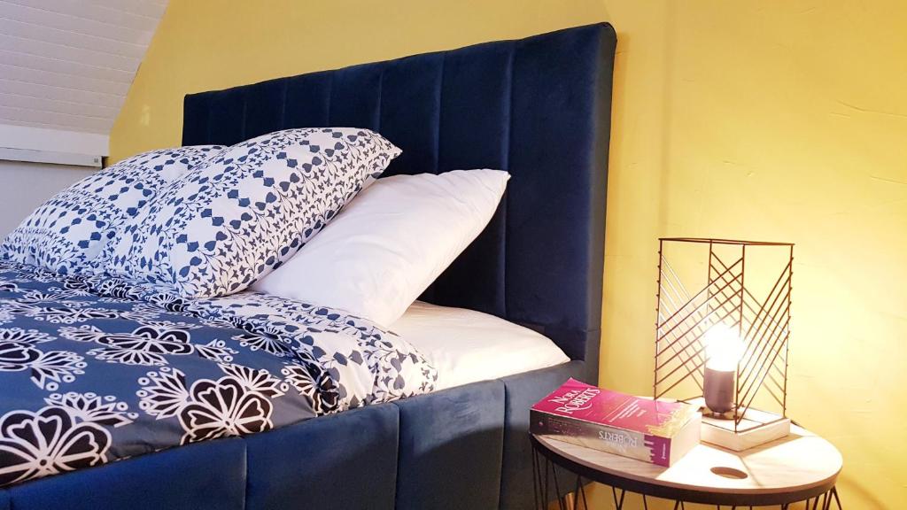 a bed with a blue headboard and a table with a lamp at KerElo Le Ptit St Roch, maisonnette cosy, mer 5km, Ploudalmezeau in Ploudalmézeau