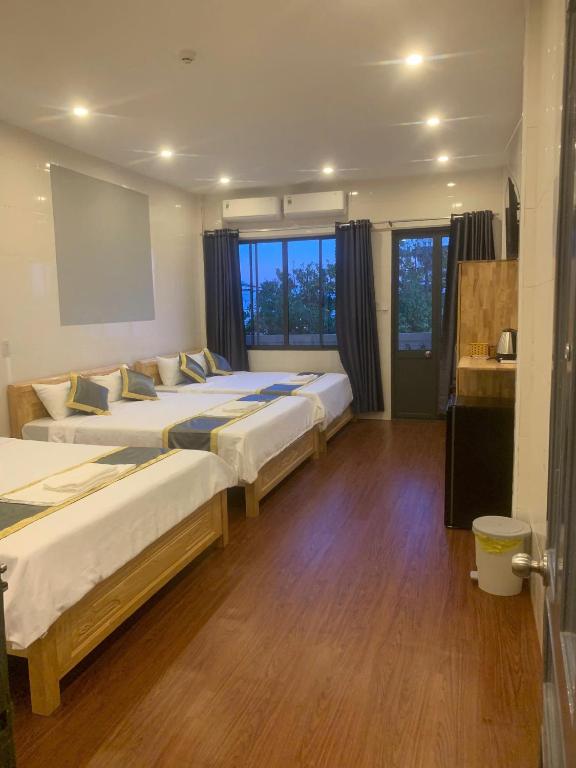 a room with three beds and a large window at Hai Dang Hotel in Can Tho
