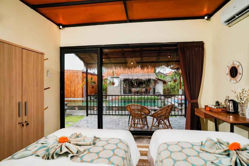 ein Schlafzimmer mit zwei Betten und einem Balkon in der Unterkunft Nila Chandra Bungalows in Ubud