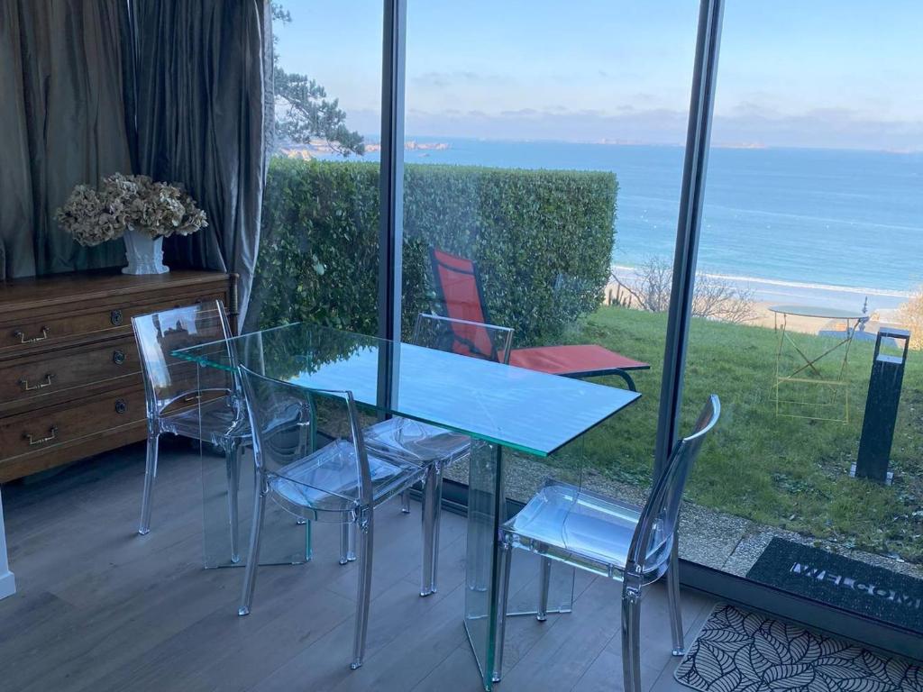 une table et des chaises en verre avec vue sur l'océan dans l'établissement Appartement rénové avec jardin, WIFI, parking à 750m de la plage à Perros-Guirec - FR-1-368-452, à Perros-Guirec