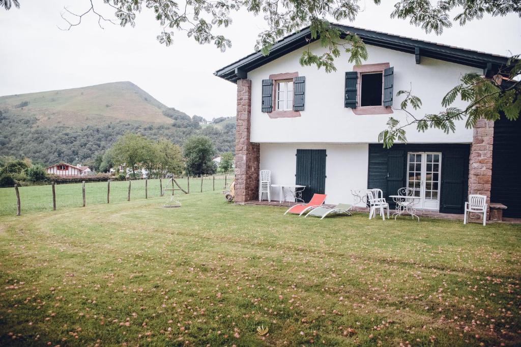 une maison blanche avec des chaises et des tables dans une cour dans l'établissement Hôtel Barberaenea, à Bidarray