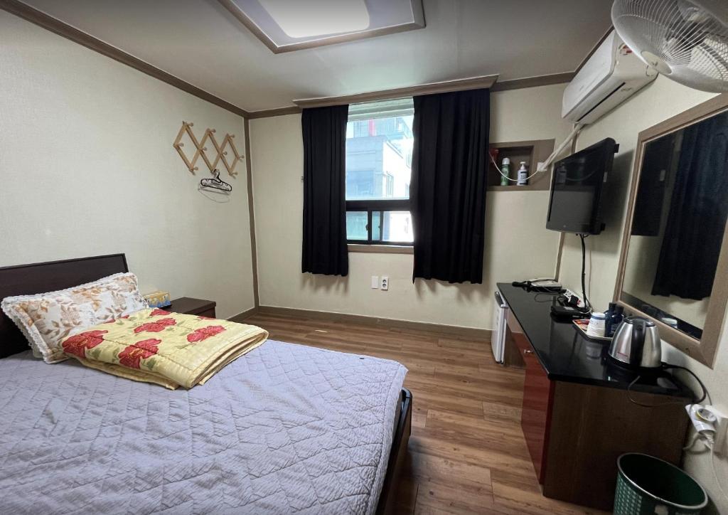 a bedroom with a bed and a desk and a television at Sangmu Green Hotel in Gwangju