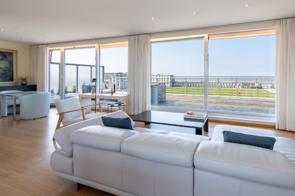 a living room with a white couch and a large window at Penthouse Ostend with Seaview in Ostend