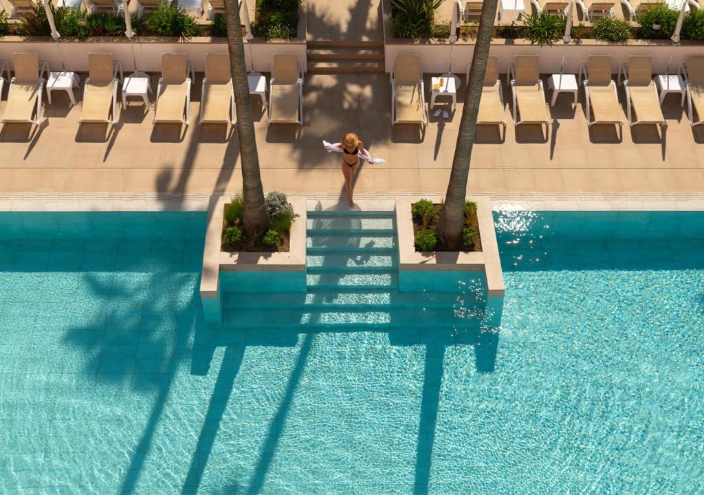 a woman standing on a stairway next to a swimming pool at AQUA Hotel The Breeze & Spa - All Inclusive - Adults Only - 4Sup in Santa Susanna