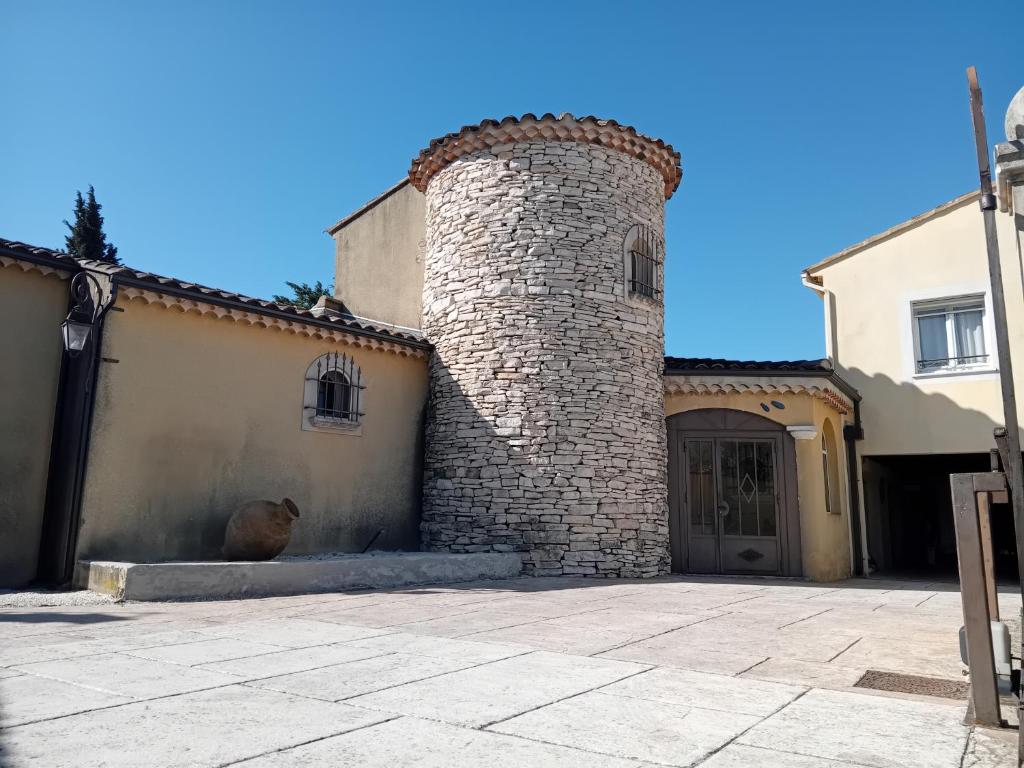 un bâtiment avec une tour en briques à côté d'un garage dans l'établissement Villa provençale avec jacuzzi, à Entraigues-sur-la-Sorgue
