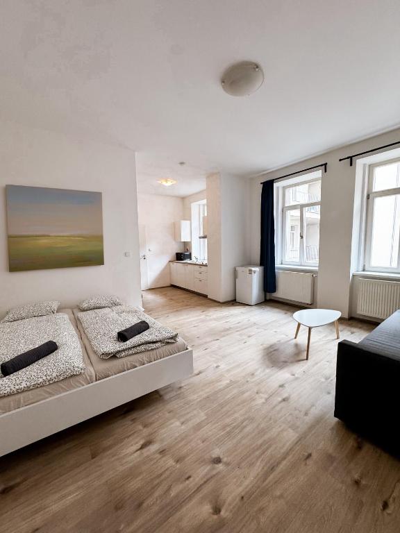 a white bedroom with a large bed and wooden floors at Nook & Nite Apartments in Brno