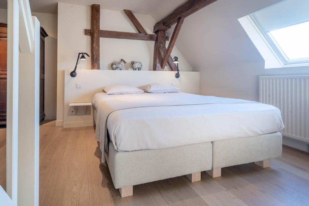 a bedroom with a large bed with white sheets at Domein Marsnil in Heers