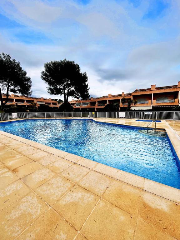 a swimming pool with blue water in front of a building at Le nid du Pradet - Piscine, tennis, plage à 5 min à pied in Le Pradet