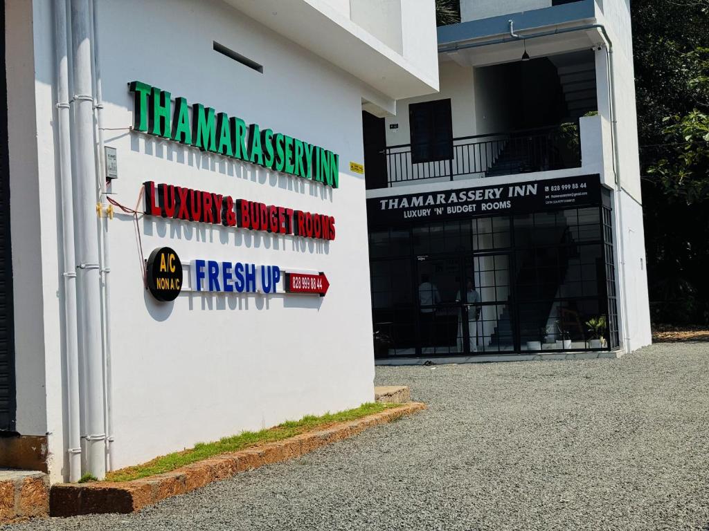 a white building with signs on the side of it at Thamarassery INN luxury and Budget Rooms in Thamarassery
