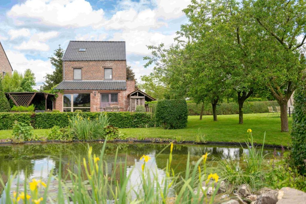 a house with a pond in front of it at Vakantiehuis Marsnil in Heers