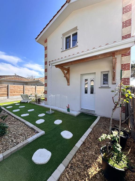 une arrière-cour avec un putting-green et une maison dans l'établissement Maison Calista, à Lanton