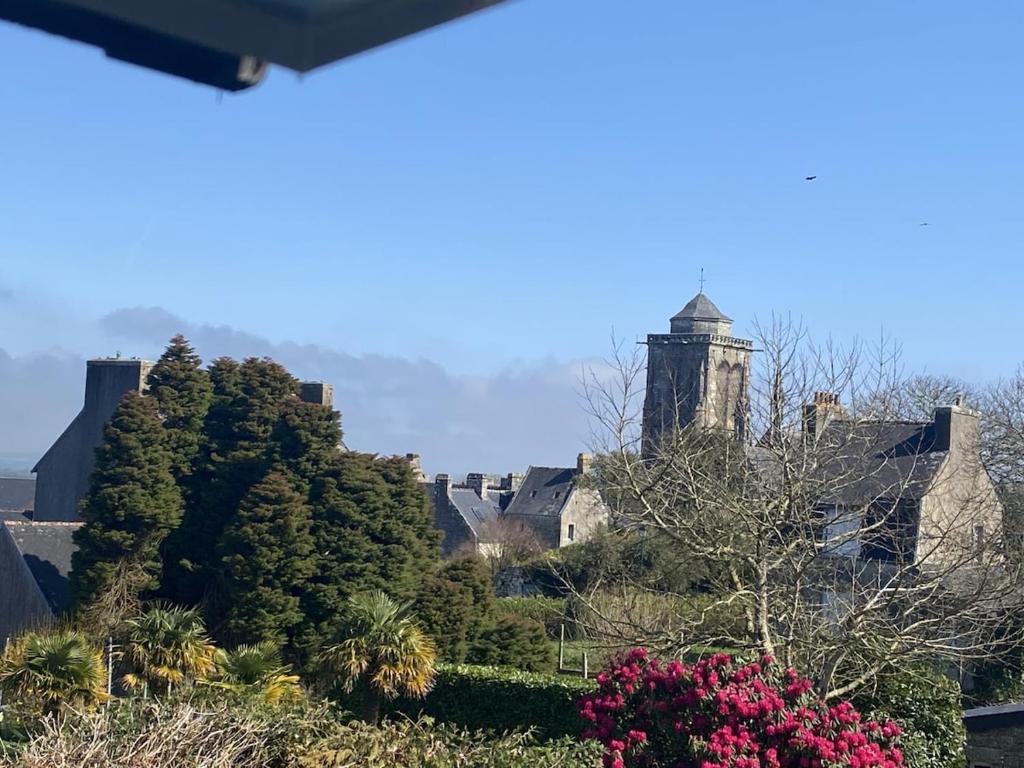 une maison avec une tour, des arbres et des fleurs dans l'établissement Maison récente au coeur du village historique, à Locronan
