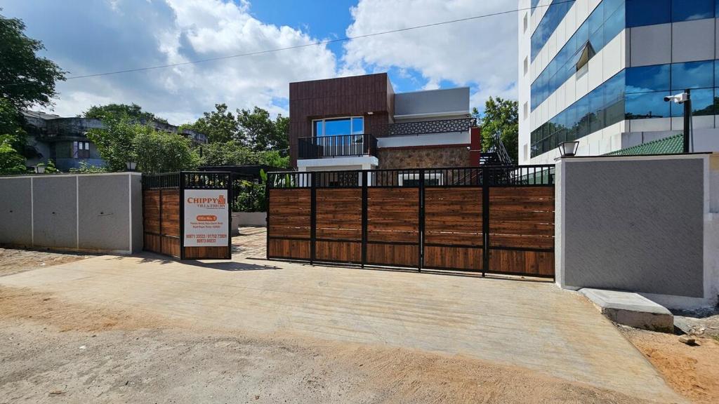 a fence in front of a house with a building at Chippy Villa No 5 Tiruchirappalli in Tiruchchirāppalli