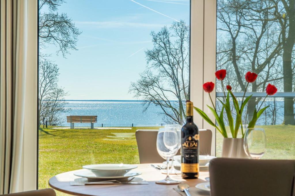 a table with a bottle of wine and flowers on it at Terrassenwohnung "Haffromantik" in Garz
