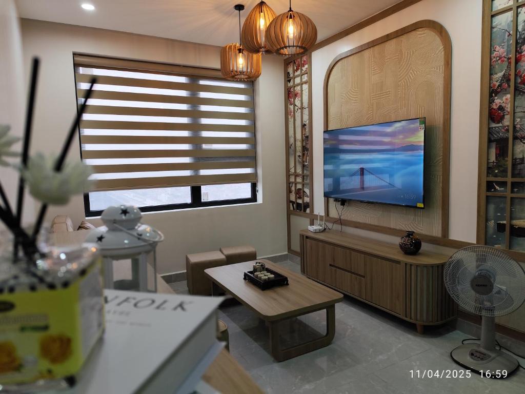 a living room with a flat screen tv next to a window at Nhà Nắng Vàng in Hai Phong