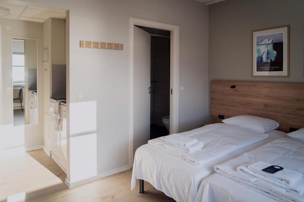 a bedroom with two beds and a mirror at HOTEL SØMA Ilulissat in Ilulissat