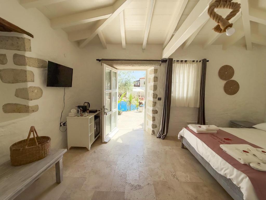 1 dormitorio con 1 cama, TV y puerta en La Grenadine Hotel, en Alacati