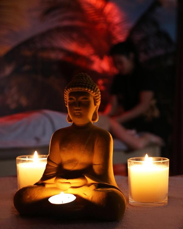 a statue of a buddha sitting next to candles at Doanesia Premium Hotel & Spa in Tirana