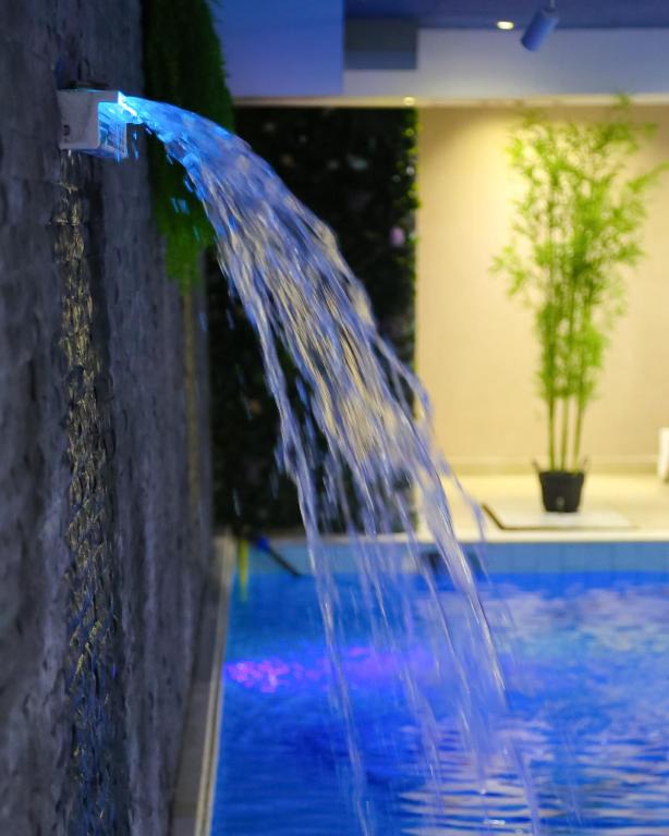 a water fountain in front of a swimming pool at Doanesia Premium Hotel & Spa in Tirana