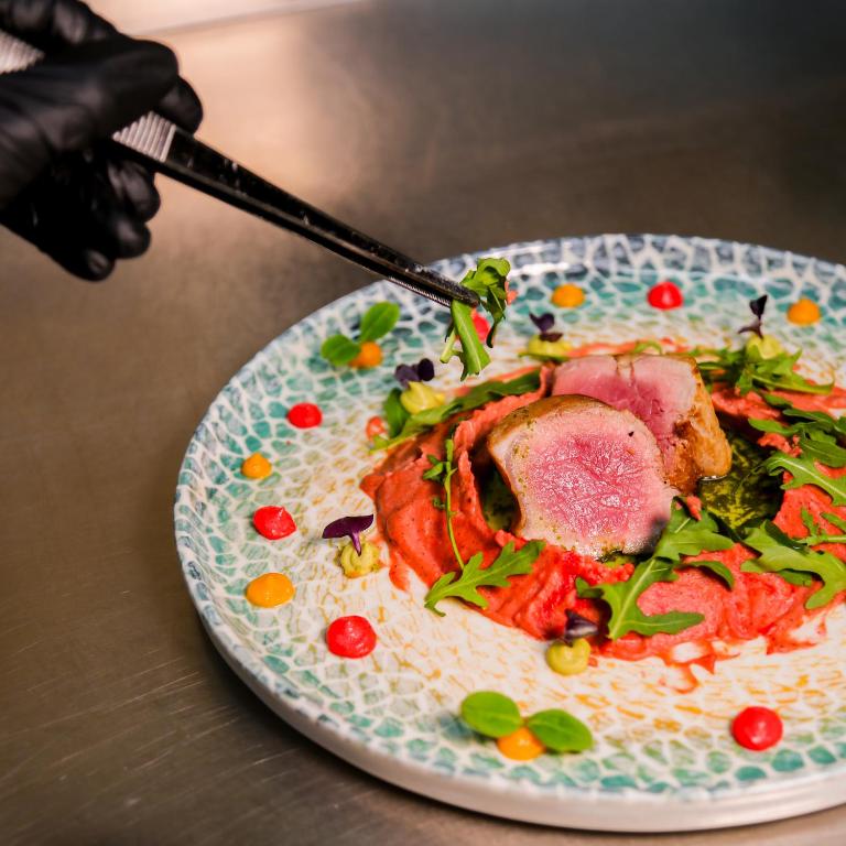 a plate of food with meat and vegetables on a table at Doanesia Premium Hotel & Spa in Tirana