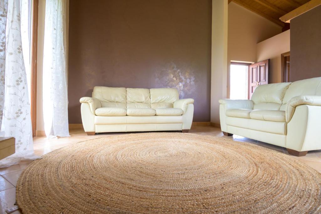 a living room with two white couches and a rug at all'ombra dei castagni in Carbognano