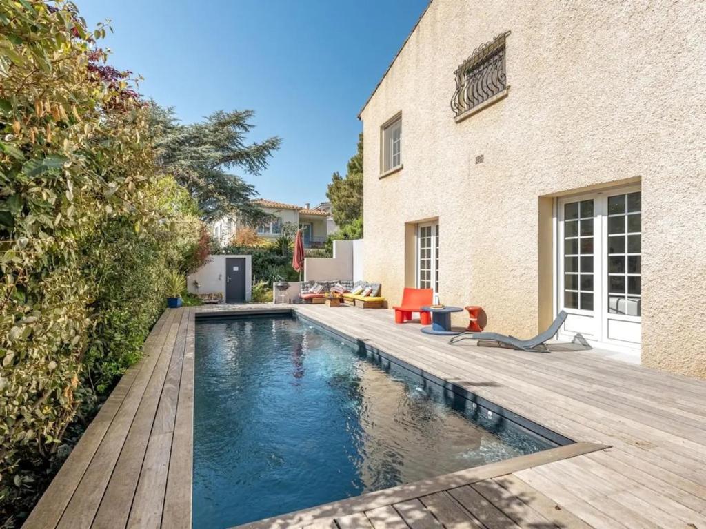 a swimming pool with a wooden deck next to a house at Maison des Artistes - Centre Ville in Narbonne
