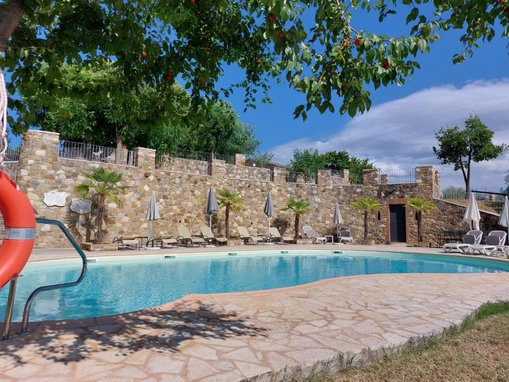 a swimming pool in front of a stone wall at Dimora Senea - Stunning Panoramic Pool in Rapolano Terme