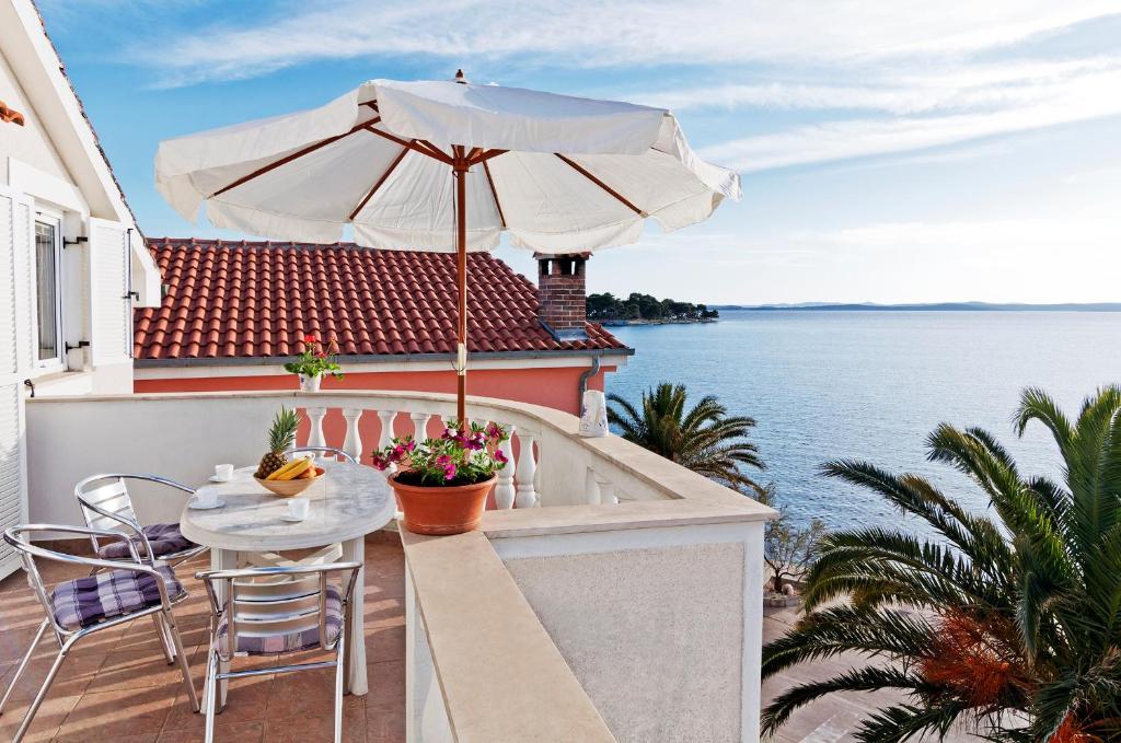 - une terrasse avec une table, un parasol et l'eau dans l'établissement Apartments Bruno, à Petrčane