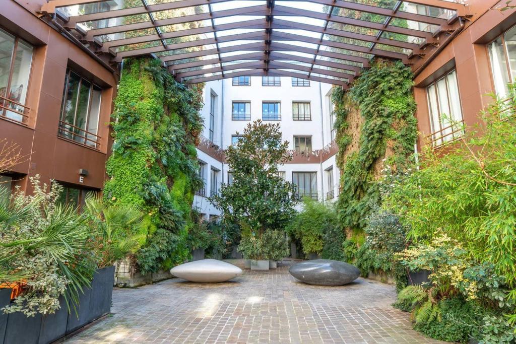 une cour avec des plantes et des bancs dans un bâtiment dans l'établissement GuestReady - Artist Loft with a Vertical Garden, à Paris