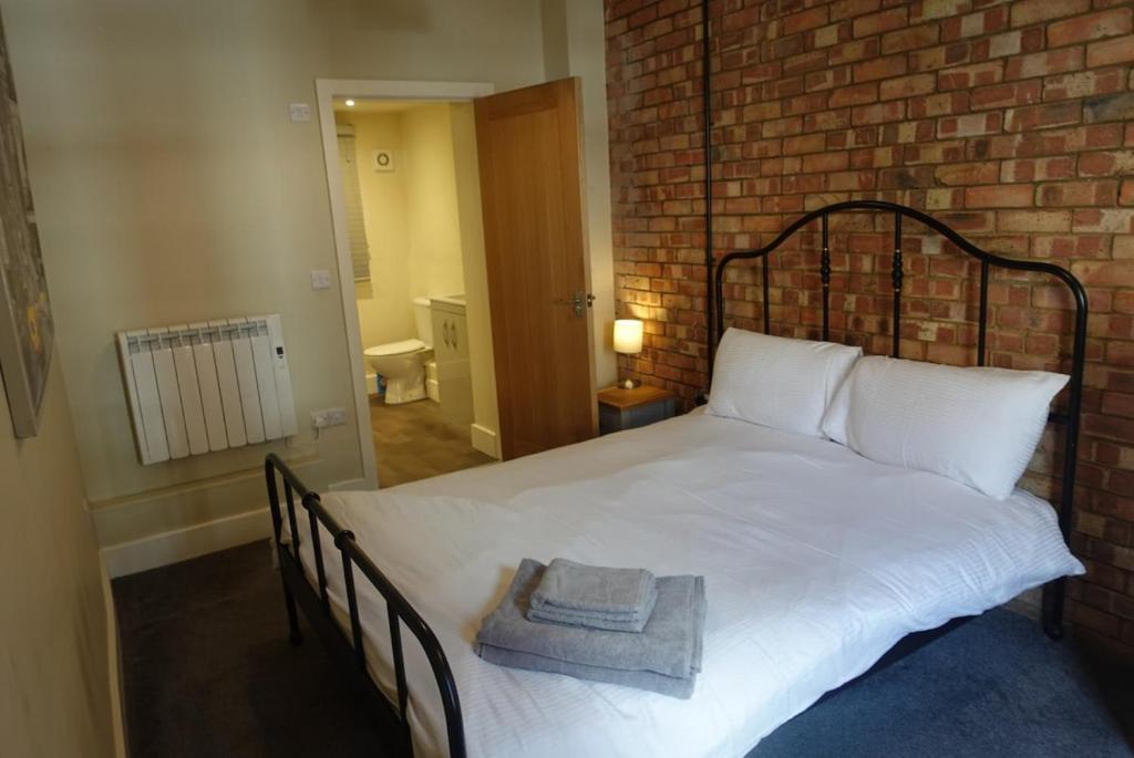 een slaapkamer met een wit bed en een bakstenen muur bij Unique, City-Center Location in Salisbury