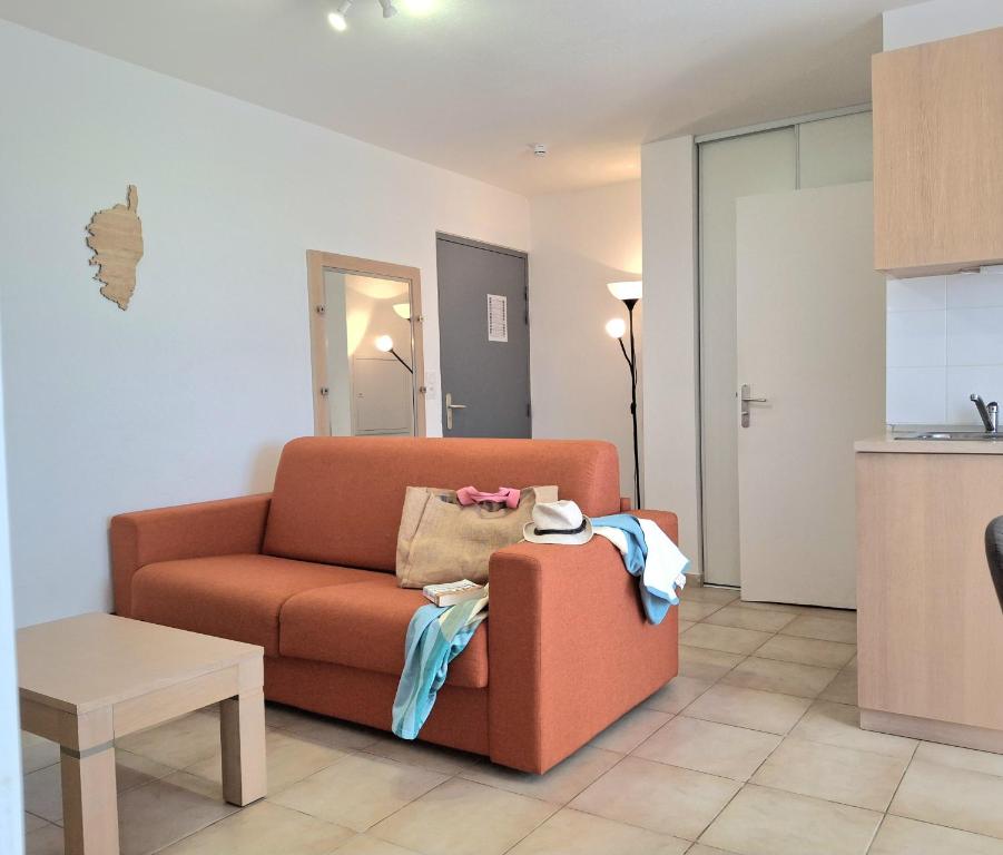 - un salon avec un canapé orange et une table dans l'établissement Villas MELODY - Appartement climatisé 4/6 pers, à Santa-Maria-Poggio