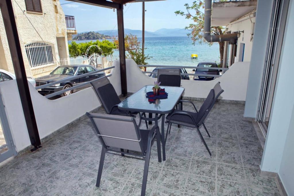 a table and chairs on a balcony with the ocean at Sophia's Summer Residence in Tolo