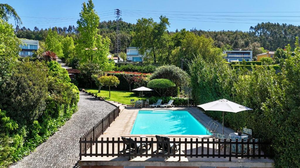 einen Pool mit Stühlen und Sonnenschirmen im Hof in der Unterkunft Vibrant Host Solutions-Aldeia da Graça in Guimarães