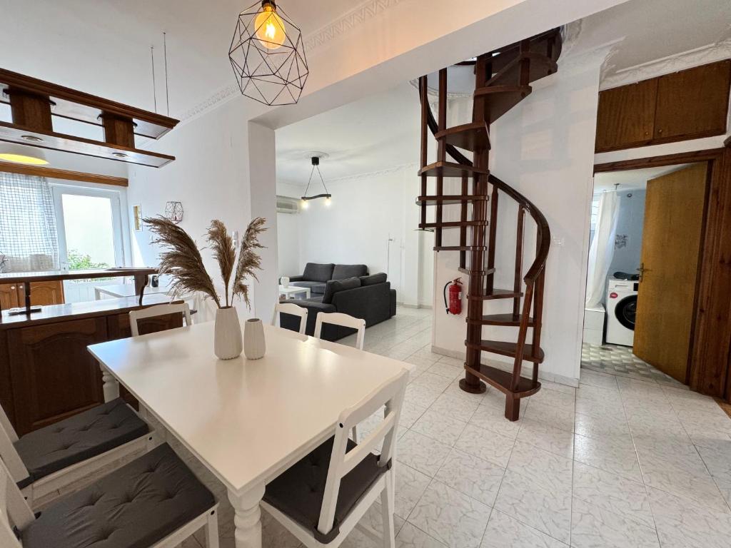 a living room with a white table and a spiral staircase at Evelyn House in Samos