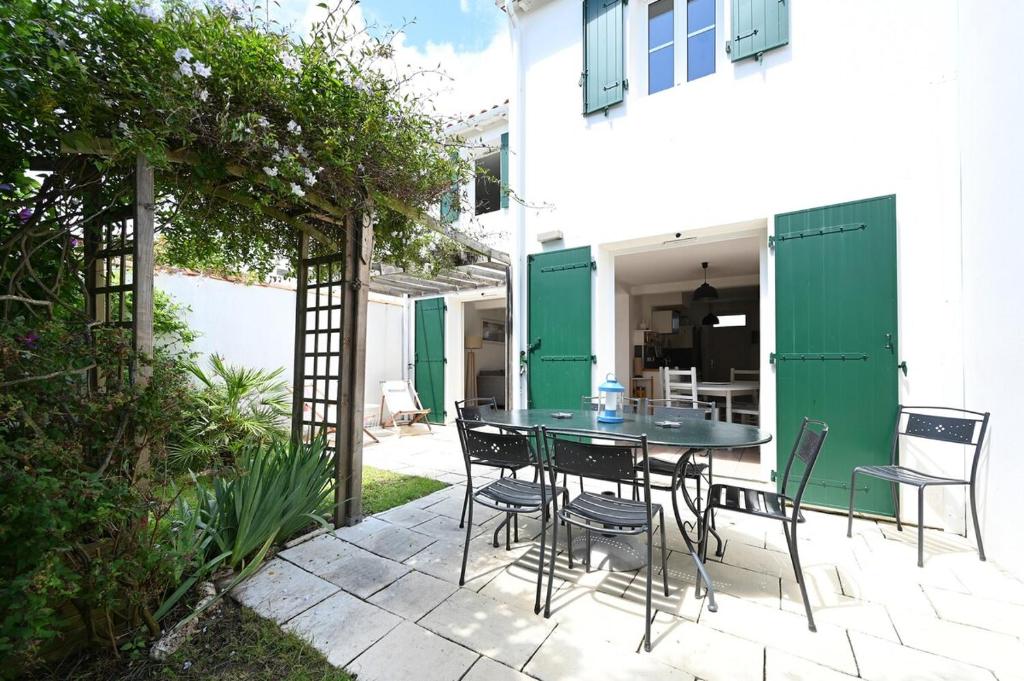 une terrasse avec une table et des chaises ainsi qu'une maison dans l'établissement 520 Le Petit Phare Village House, à Saint-Clément-des-Baleines