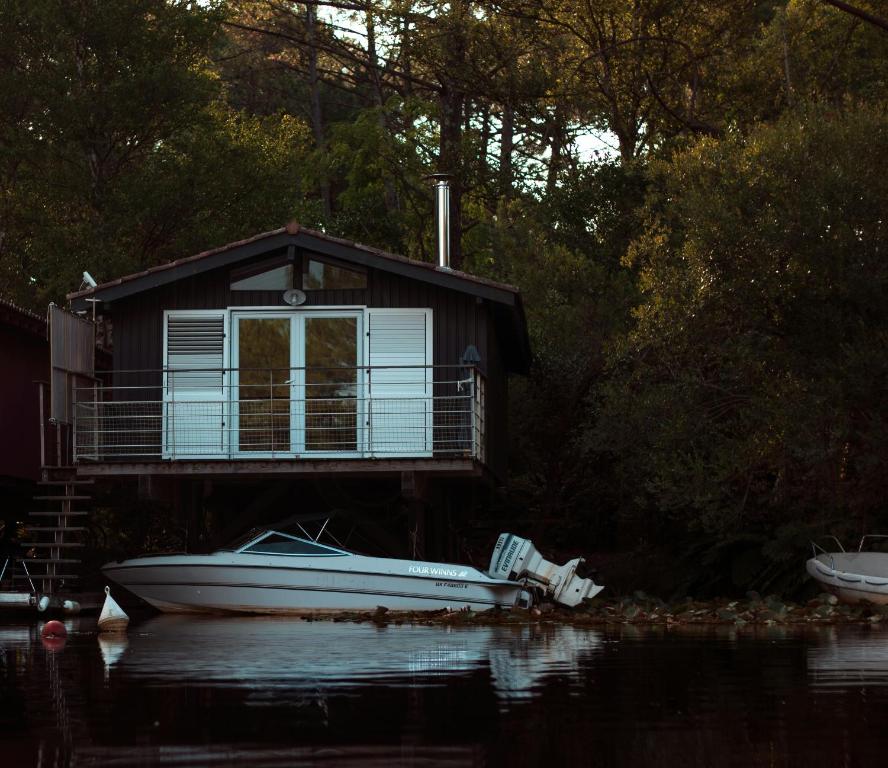 un bateau garé devant une maison sur l'eau dans l'établissement Stilted Cabin By Lake Lacanau, à Lacanau